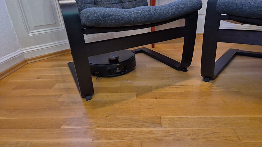 Der MOVA Z60 Ultra Roller mit eingefahrenem Flexcope-Laserturm unter einem flachen Sideboard.